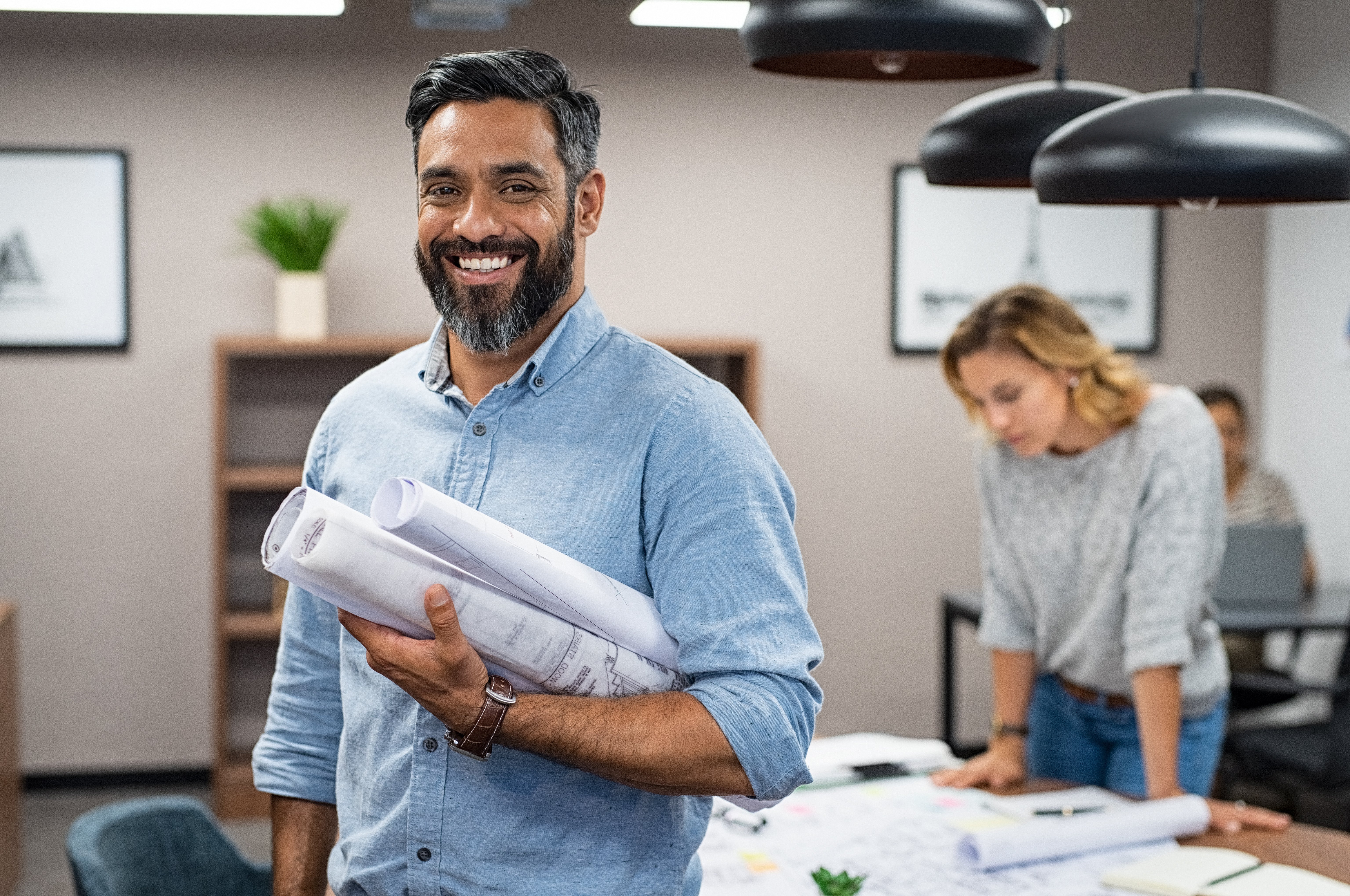 A male architect and business owner holding his designs and smiling