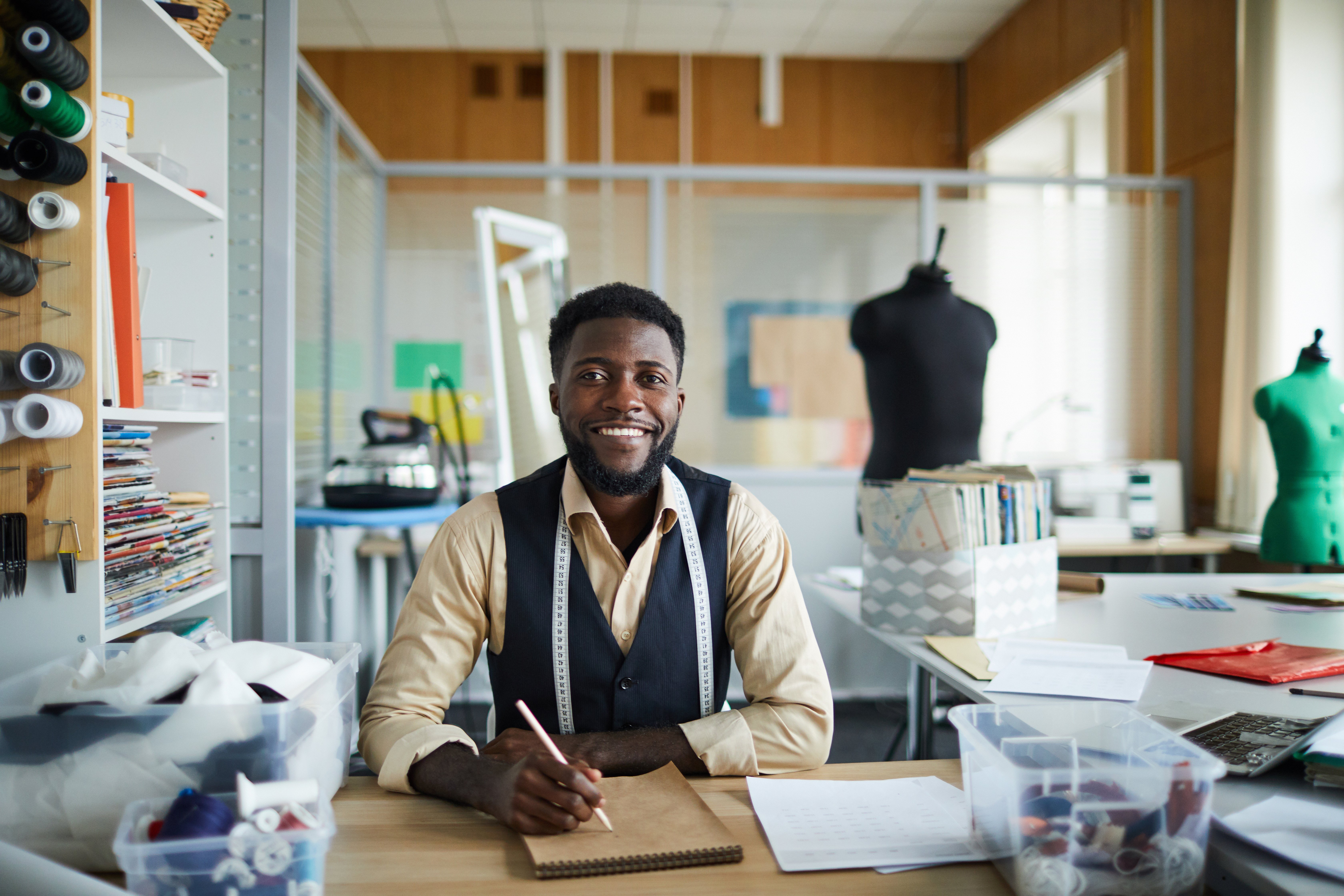 A young male clothing designer sitting at his workbench