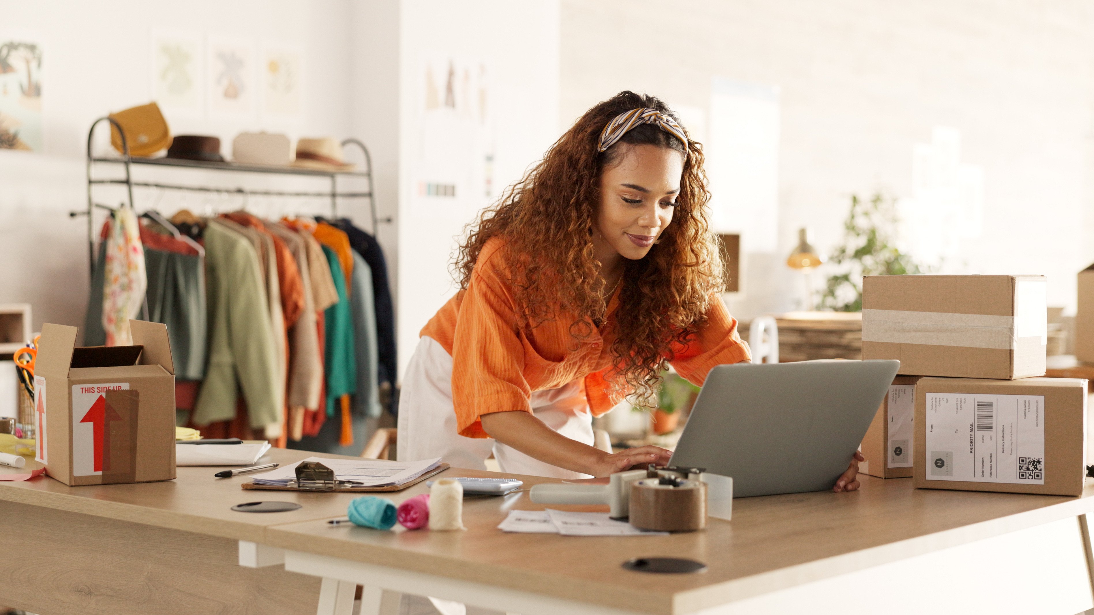 Young woman of color working on her laptop in her retail store 