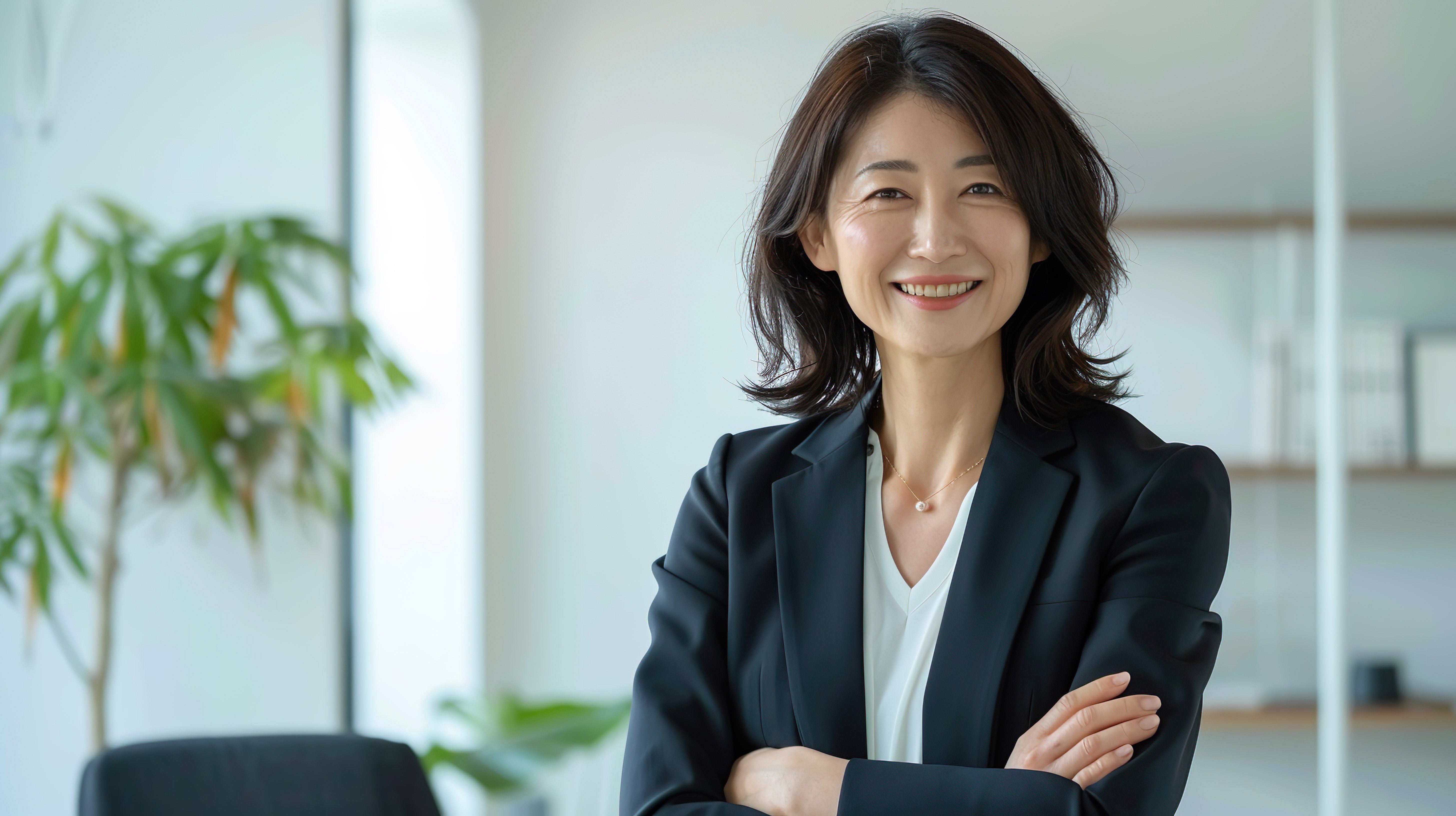 Asian woman in business suit crossing arms and smiling