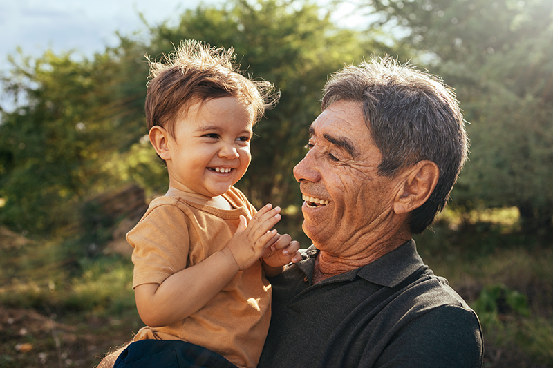 Grandpa and grandchild smiling outside 